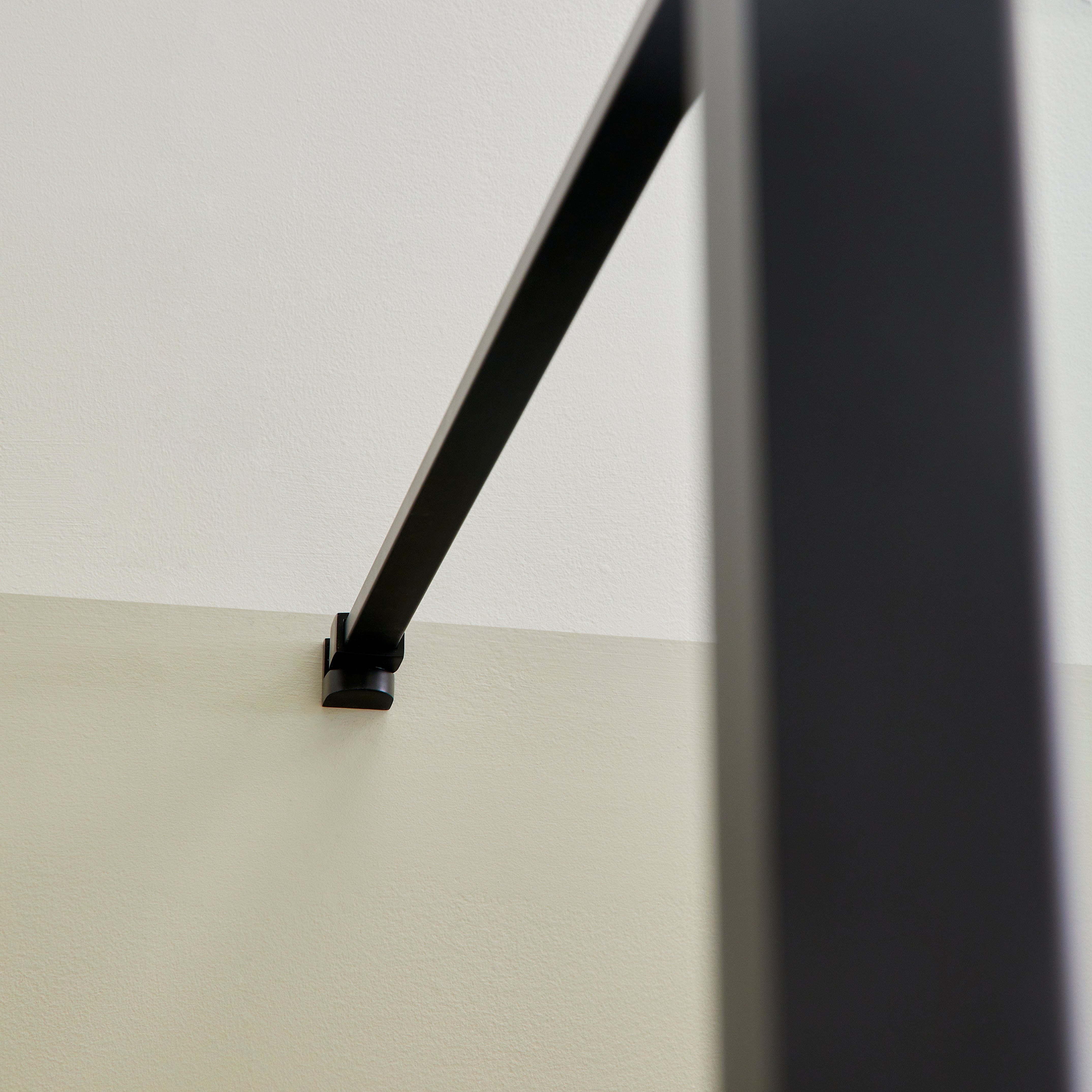 Détail du bras de support noir mat de la paroi de douche à l’italienne